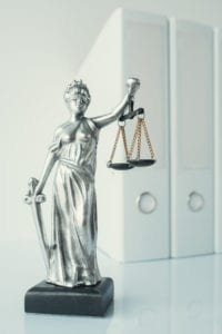 Lady Justice statue with document ring binders in law office